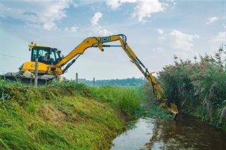 Gras uit beek halen met machine