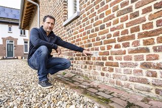Meneer wijst aan hoe hoog het water stond binnen een half uur