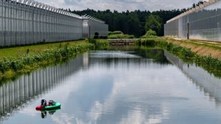 Meetboot op het water tussen kassen
