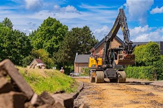 Een graafmachine die het asfalt op de Moorveldsberg verwijdert