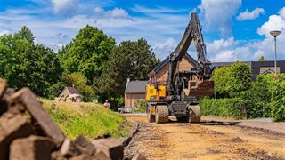 Een graafmachine die het asfalt op de Moorveldsberg verwijdert