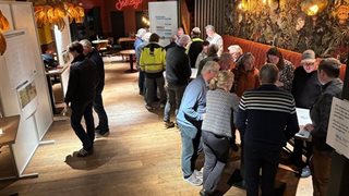Bezoekers tijdens de inloopavond stellen vragen