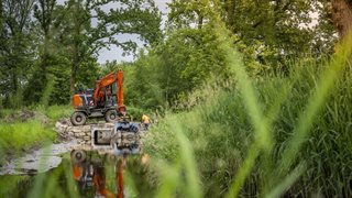 Graafmachine op brug over beekje